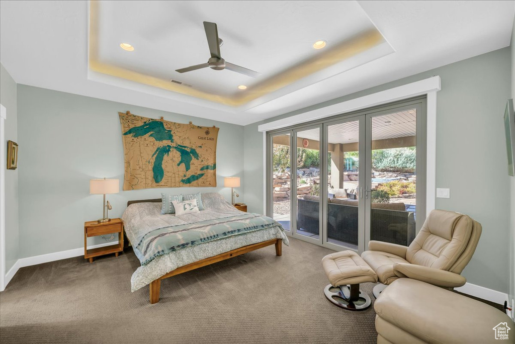 Bedroom with ceiling fan, a raised ceiling, access to outside, and carpet flooring