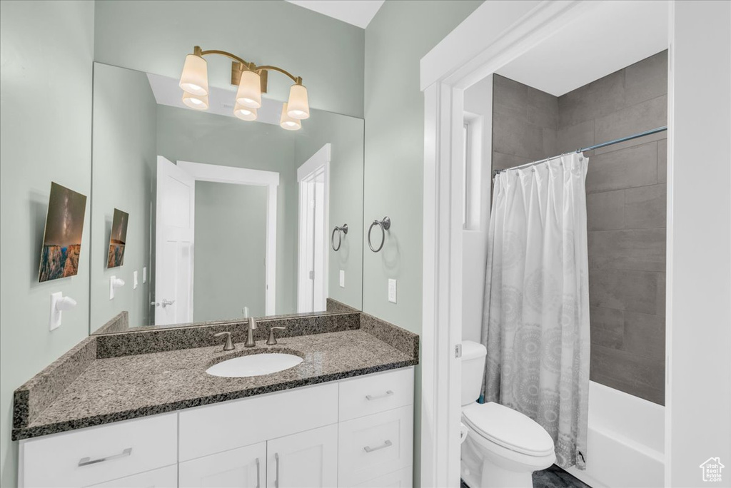 Full bathroom featuring vanity, shower / bath combination with curtain, and toilet