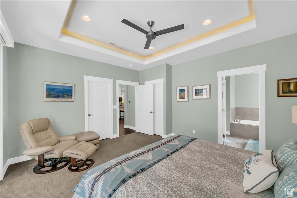 Bedroom with connected bathroom, ceiling fan, a raised ceiling, and carpet