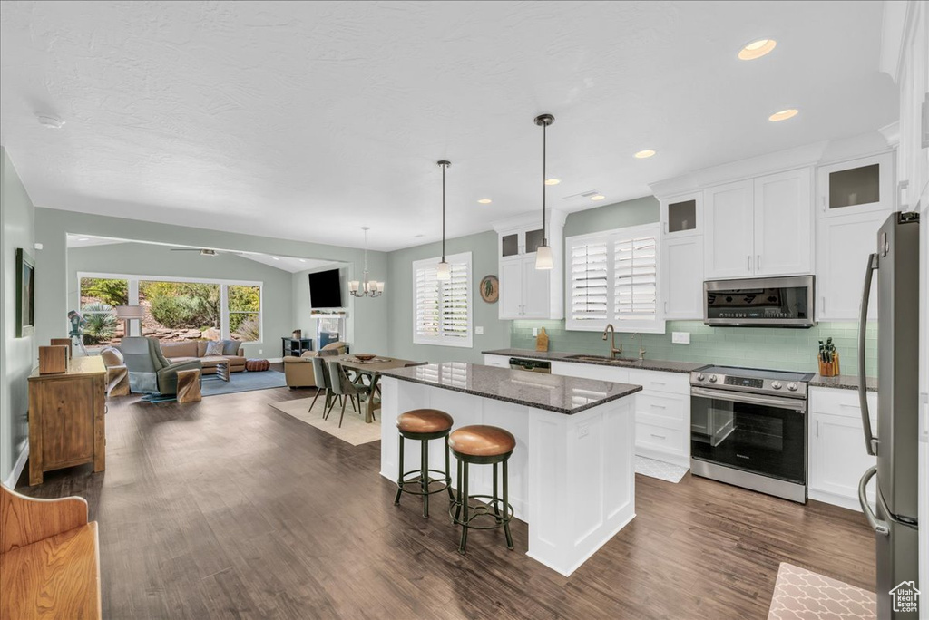 Kitchen with a center island, white cabinetry, dark wood-type flooring, and stainless steel appliances