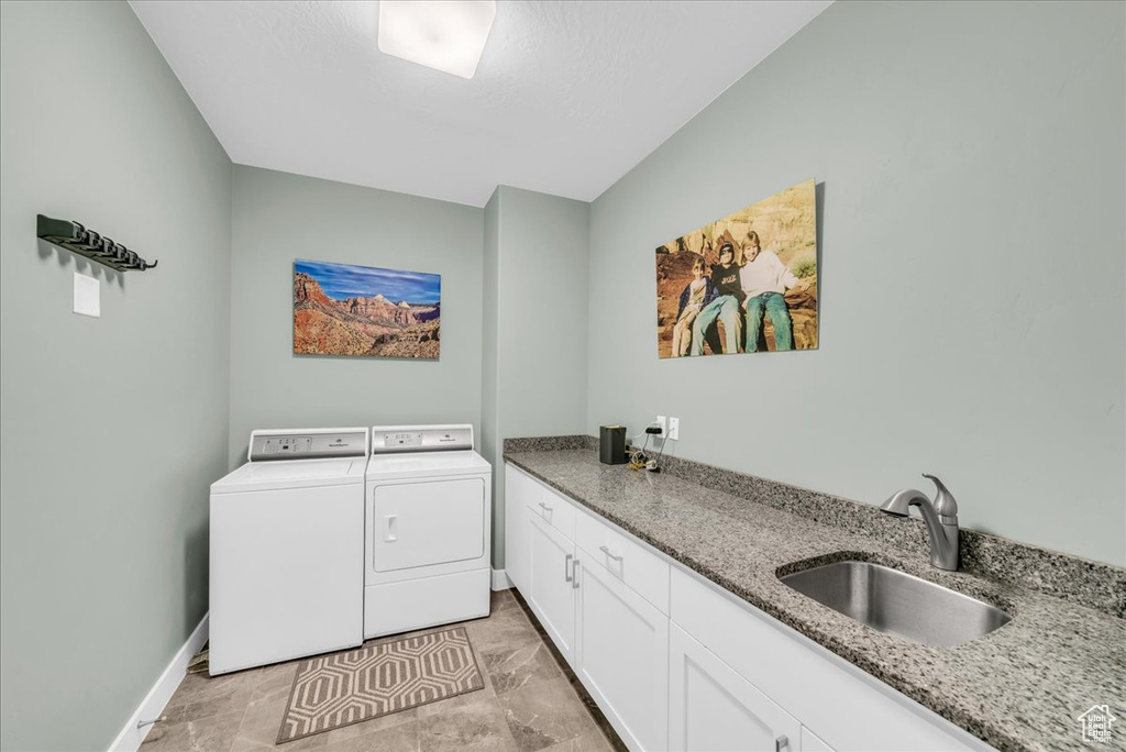 Laundry room featuring cabinets, sink, and washing machine and clothes dryer