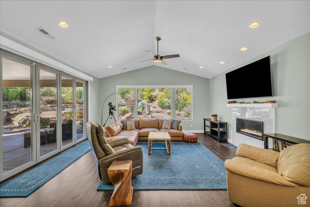 Living room featuring hardwood / wood-style floors, ceiling fan, a tile fireplace, and vaulted ceiling