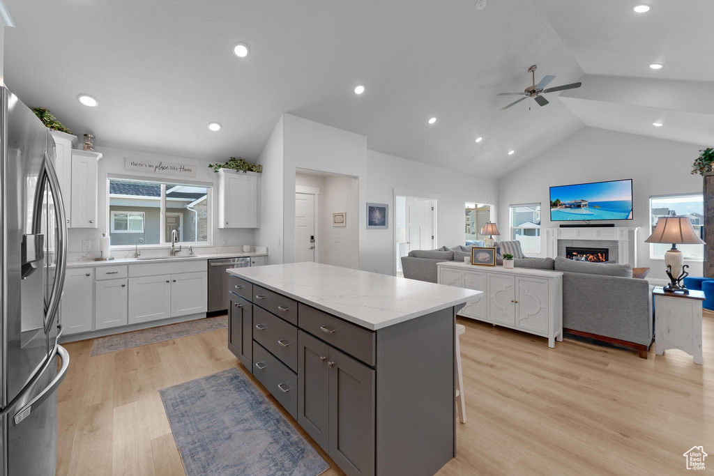Kitchen featuring white cabinetry, appliances with stainless steel finishes, plenty of natural light, vaulted ceiling, and a center island
