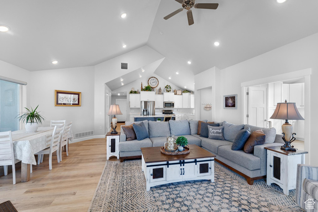 Living room with a wealth of natural light, ceiling fan, light wood-type flooring, and lofted ceiling