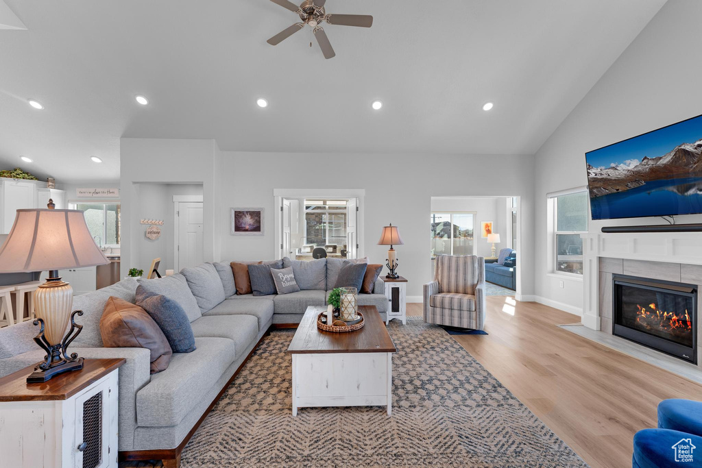 Living room featuring light wood-type flooring, ceiling fan, and high vaulted ceiling