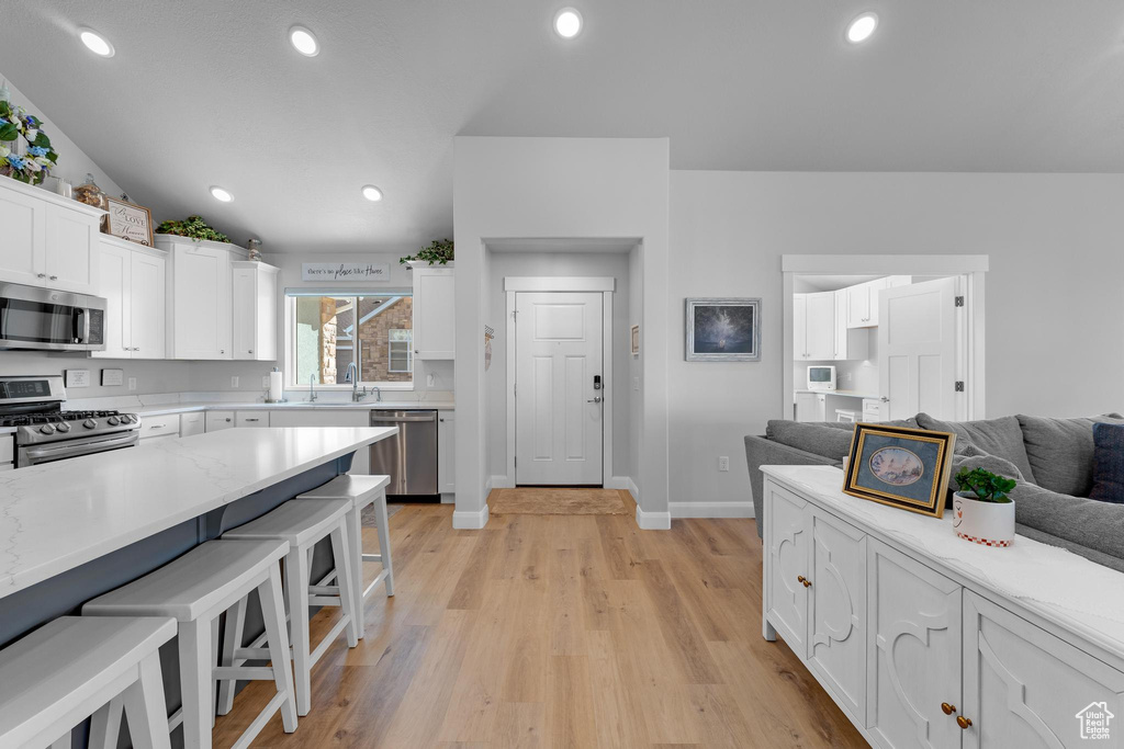 Kitchen featuring white cabinetry, a kitchen bar, light hardwood / wood-style floors, and stainless steel appliances