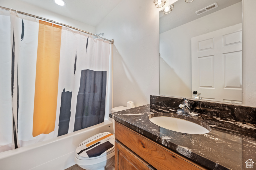 Full bathroom with vanity, shower / bath combo with shower curtain, and toilet