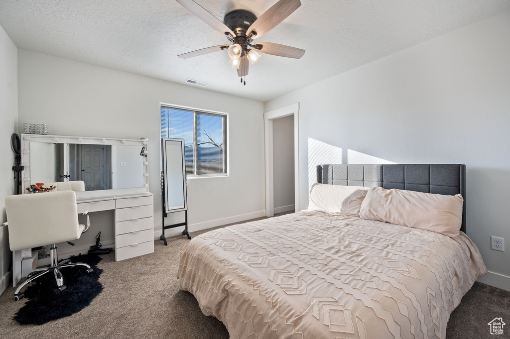 Carpeted bedroom with a textured ceiling and ceiling fan