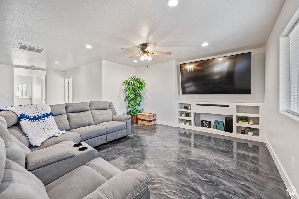 Living room with built in shelves, a textured ceiling, and ceiling fan