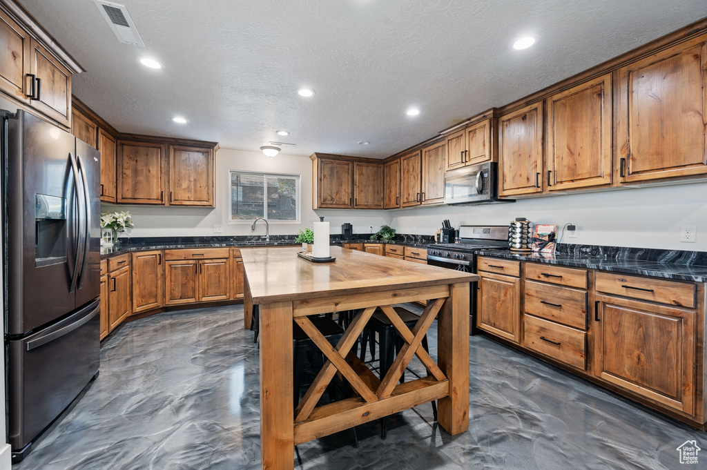Kitchen with a textured ceiling, sink, and appliances with stainless steel finishes