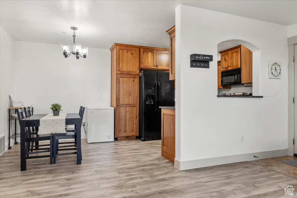 Kitchen featuring light hardwood / wood-style flooring, black appliances, decorative light fixtures, and a notable chandelier