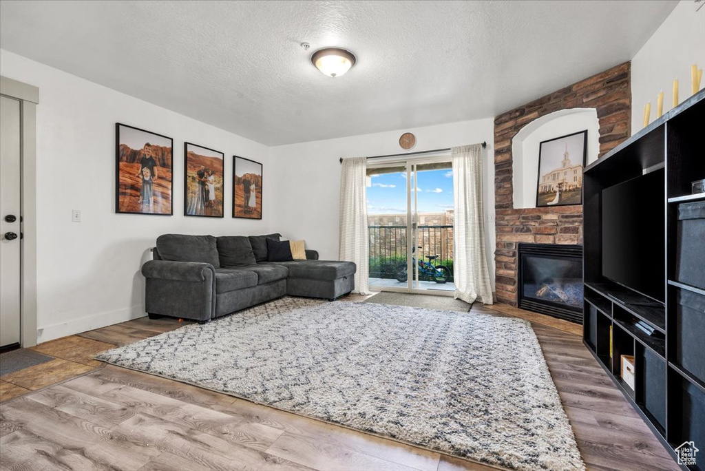 Living room with a fireplace, wood-type flooring, and a textured ceiling