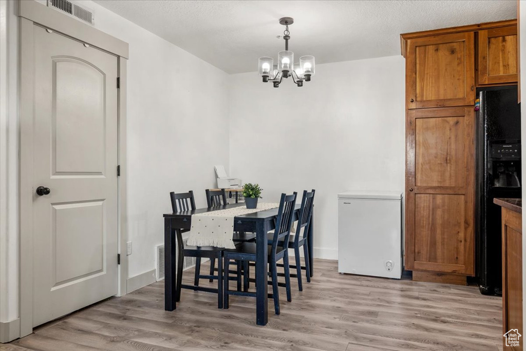 Dining space with light hardwood / wood-style floors and a chandelier