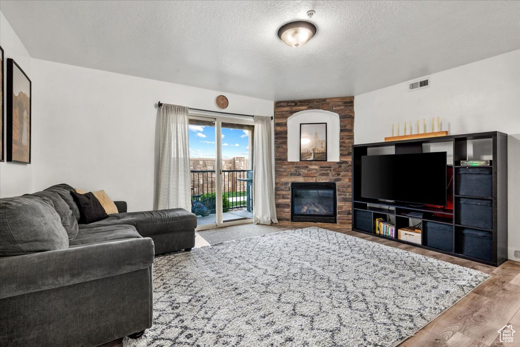 Living room featuring hardwood / wood-style floors, a fireplace, and a textured ceiling