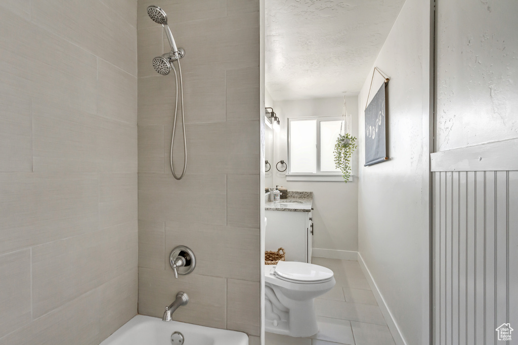 Full bathroom featuring vanity, tile patterned flooring, toilet, and tiled shower / bath combo