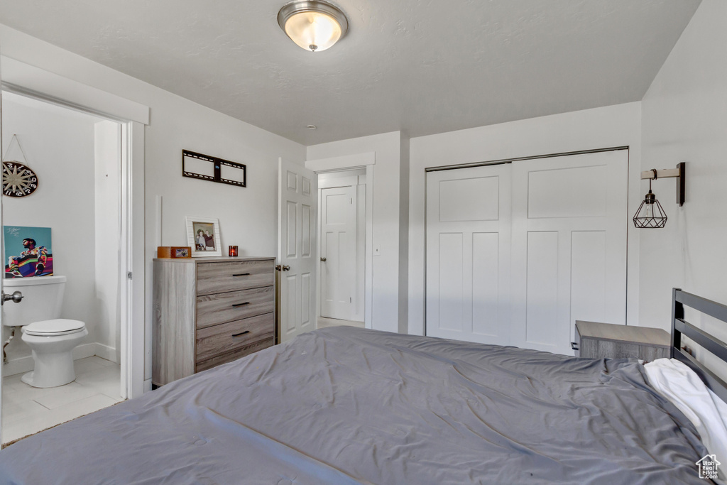 Bedroom featuring a closet, light tile patterned flooring, and ensuite bath