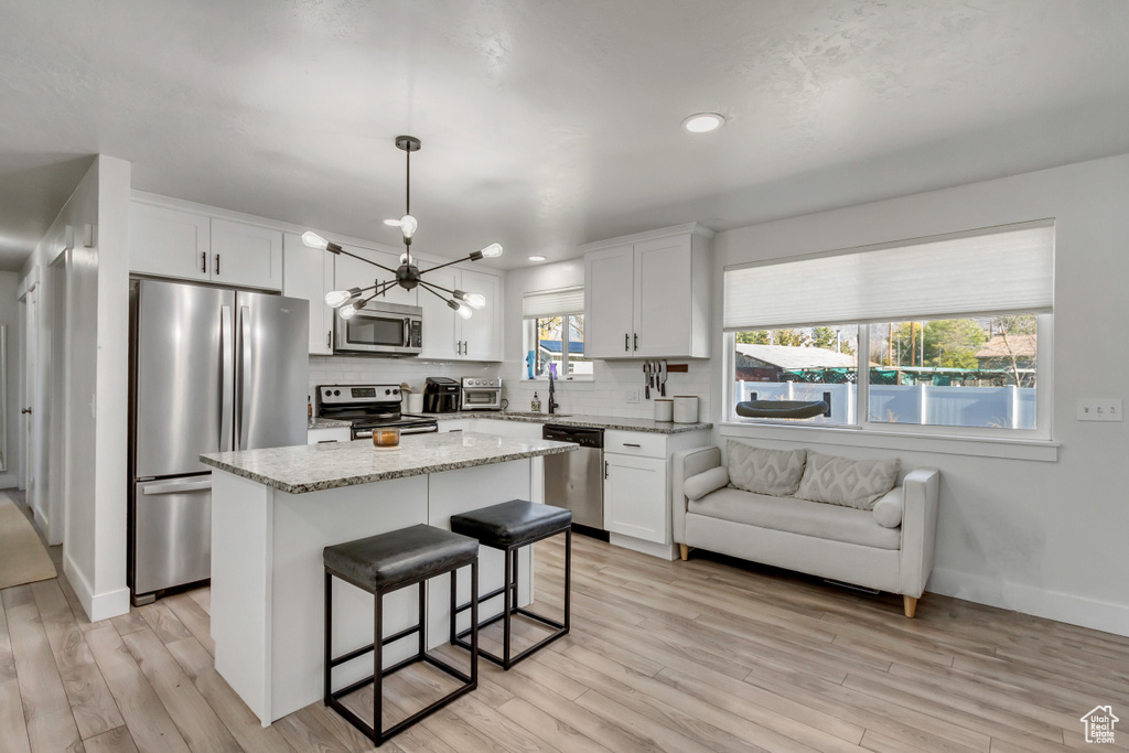 Kitchen featuring a kitchen island, light wood-type flooring, appliances with stainless steel finishes, and white cabinets