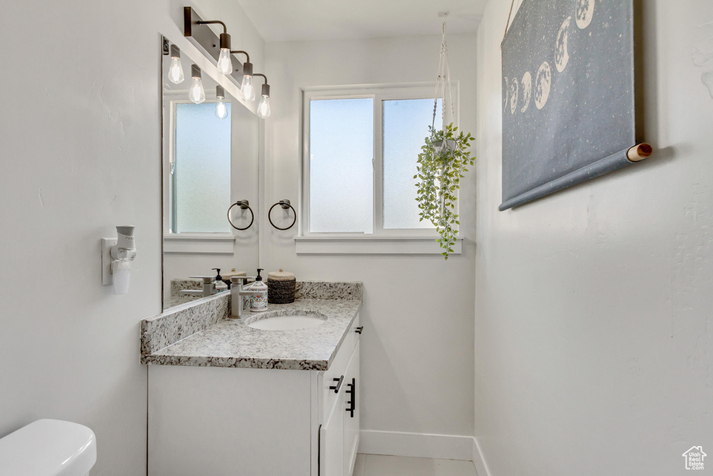 Bathroom with toilet, vanity, and a wealth of natural light