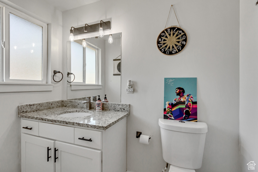 Bathroom featuring toilet, vanity, and plenty of natural light