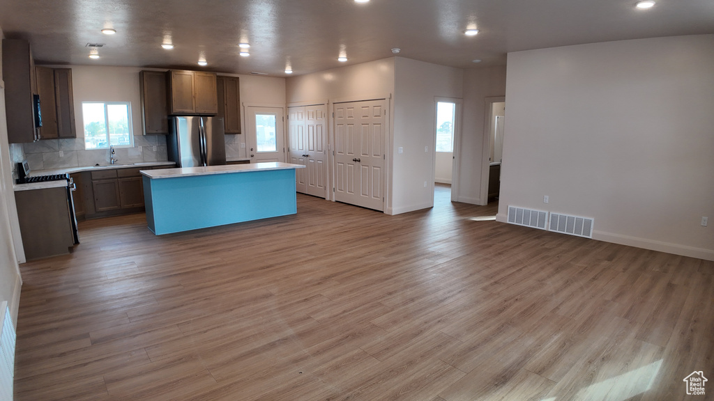 Kitchen with a kitchen island, decorative backsplash, stainless steel fridge, and light hardwood / wood-style flooring