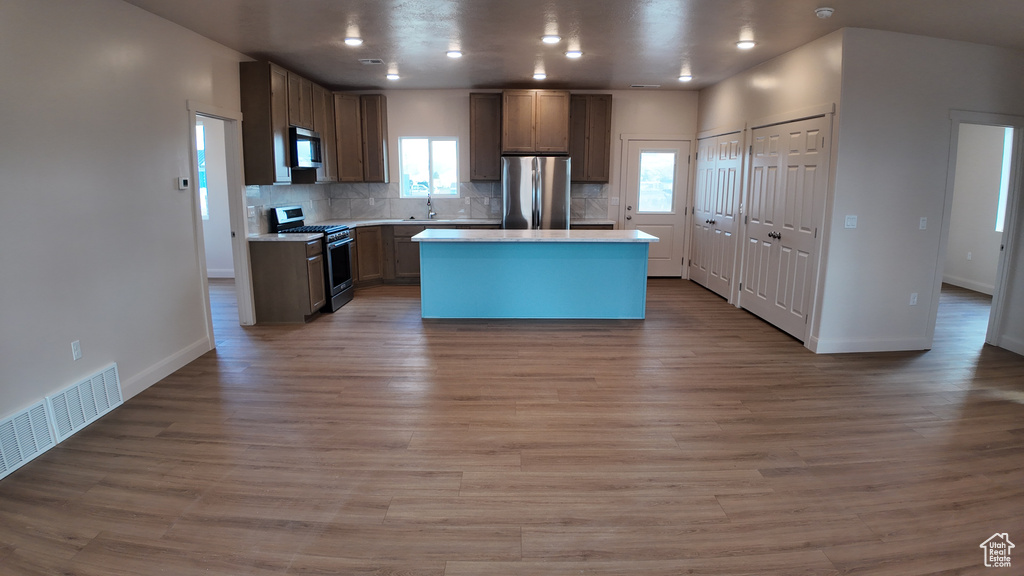 Kitchen featuring a center island, decorative backsplash, light hardwood / wood-style floors, and stainless steel appliances