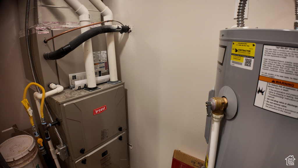 Utility room featuring heating unit and electric water heater