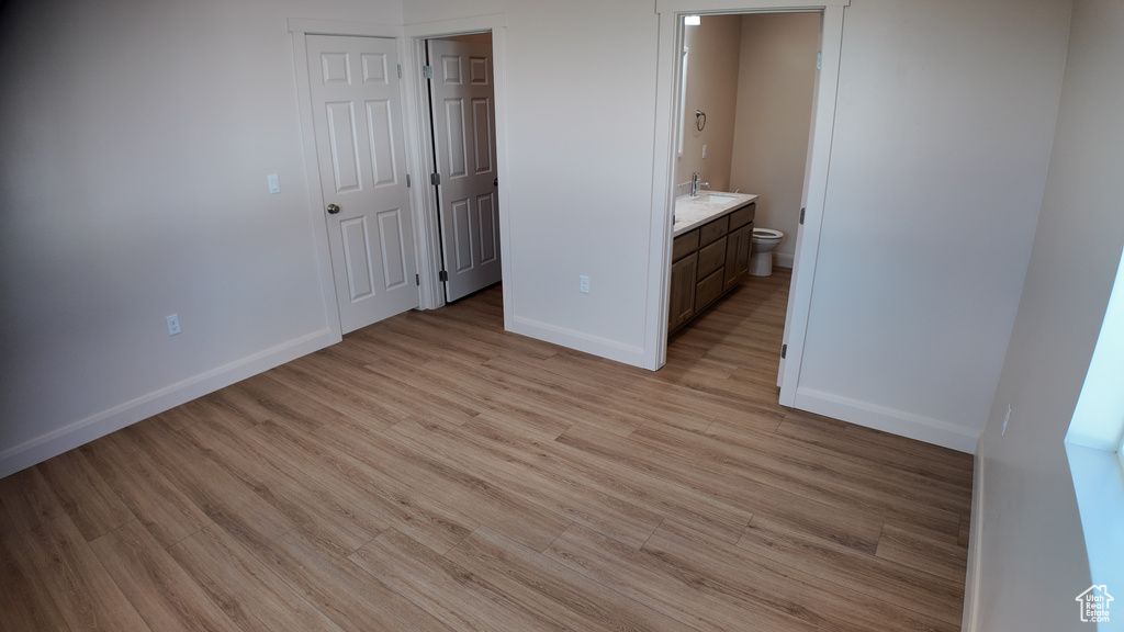 Unfurnished bedroom with ensuite bathroom, light hardwood / wood-style flooring, and sink