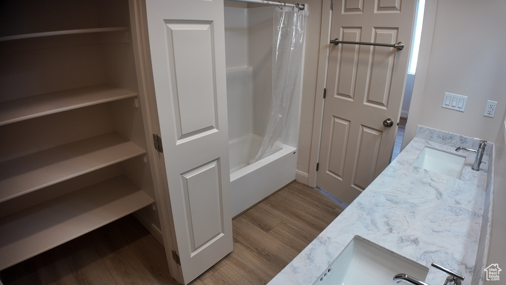 Bathroom with hardwood / wood-style floors, shower / tub combo with curtain, and vanity