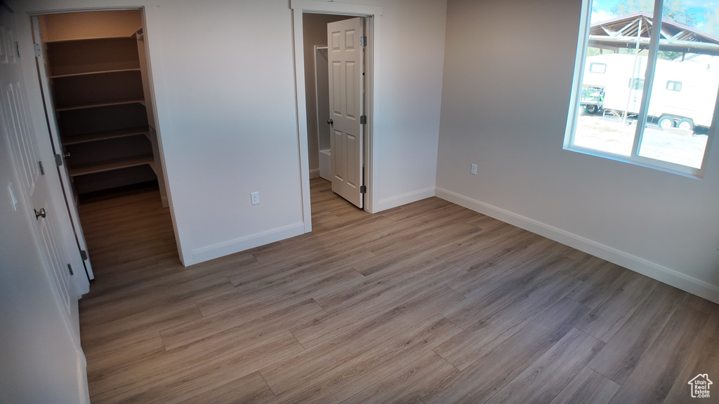 Unfurnished bedroom with light wood-type flooring, a spacious closet, and a closet