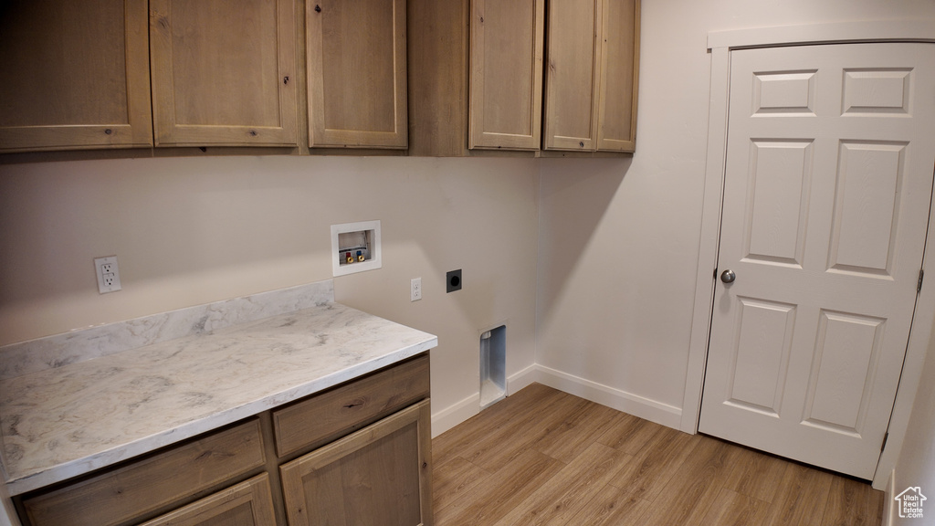 Laundry area with electric dryer hookup, washer hookup, cabinets, and light hardwood / wood-style flooring