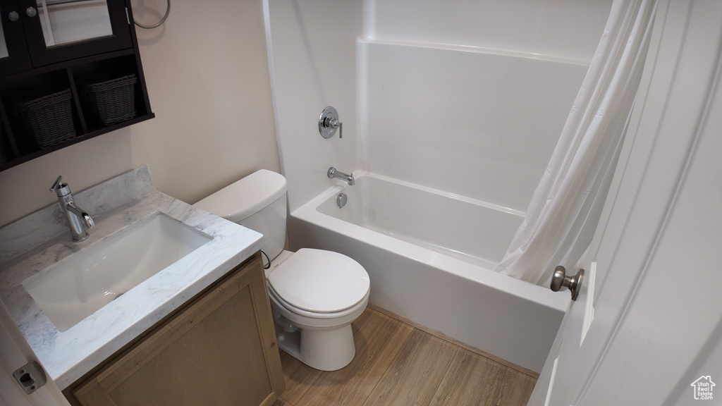 Full bathroom featuring hardwood / wood-style floors, vanity, shower / bath combo with shower curtain, and toilet