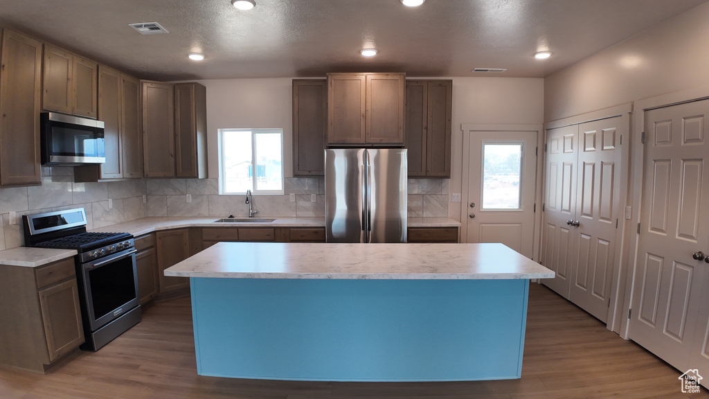 Kitchen with stainless steel appliances, a healthy amount of sunlight, and a kitchen island