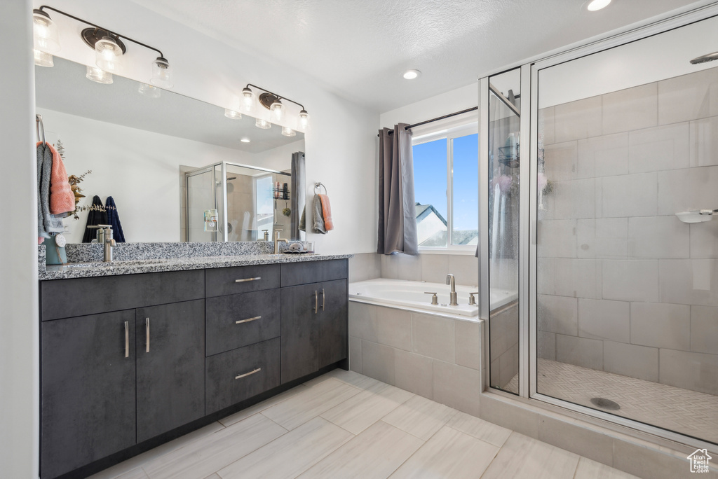 Bathroom with independent shower and bath, vanity, a textured ceiling, and tile patterned flooring