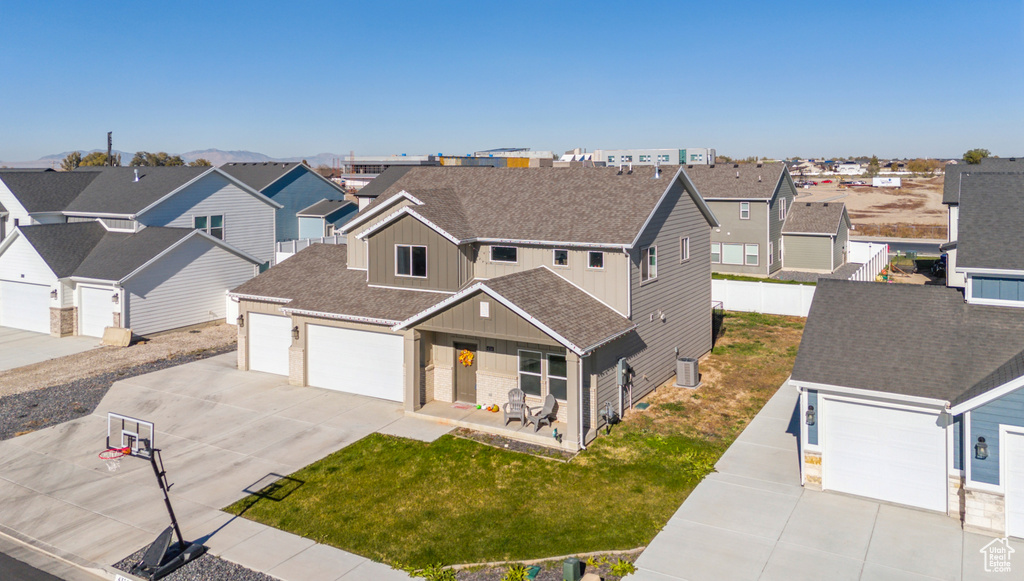 View of front of house featuring a front lawn, a garage, cooling unit, and a porch