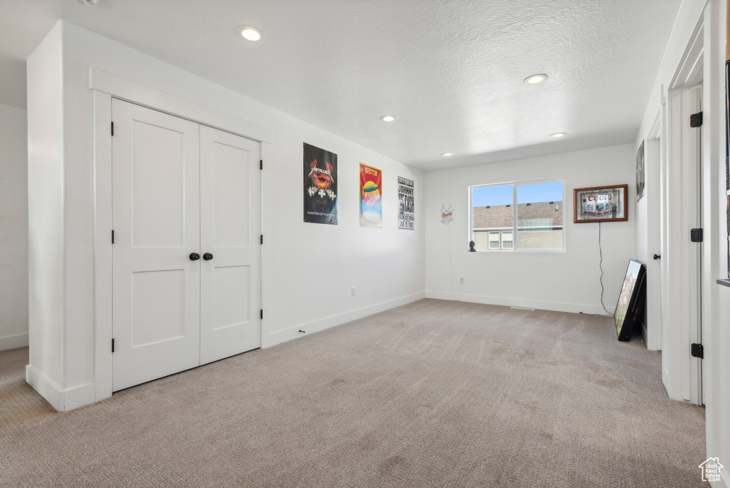 Unfurnished bedroom with a closet, a textured ceiling, and light colored carpet