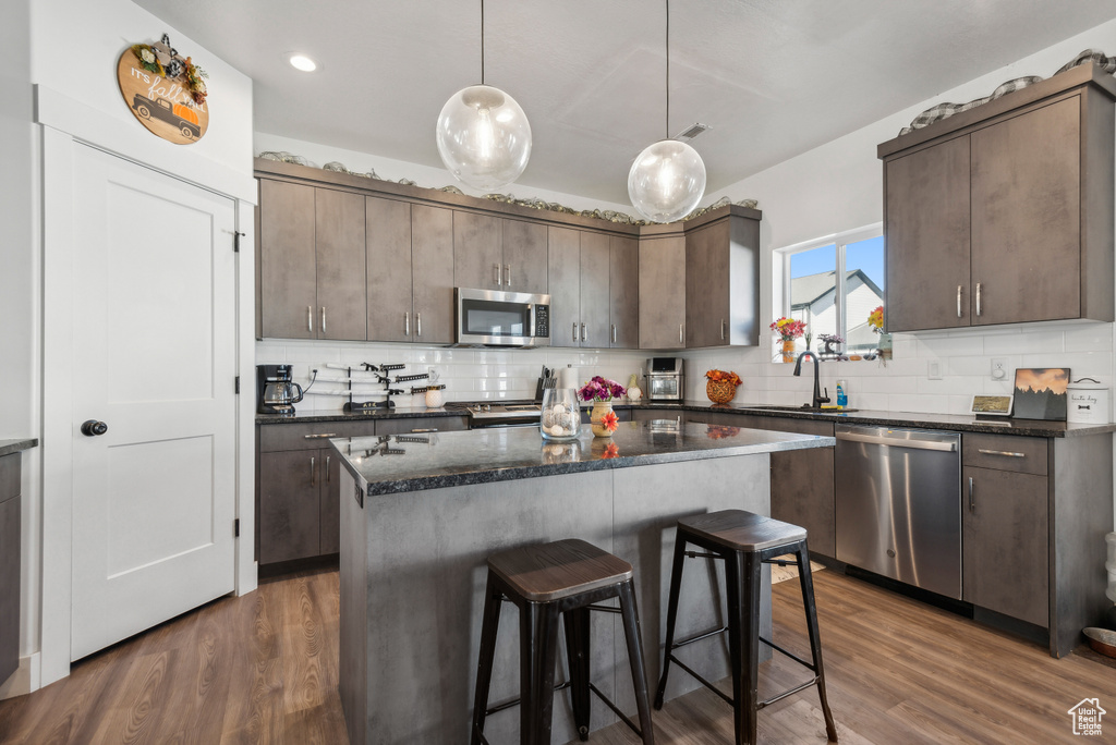 Kitchen featuring dark brown cabinetry, appliances with stainless steel finishes, and dark hardwood / wood-style flooring