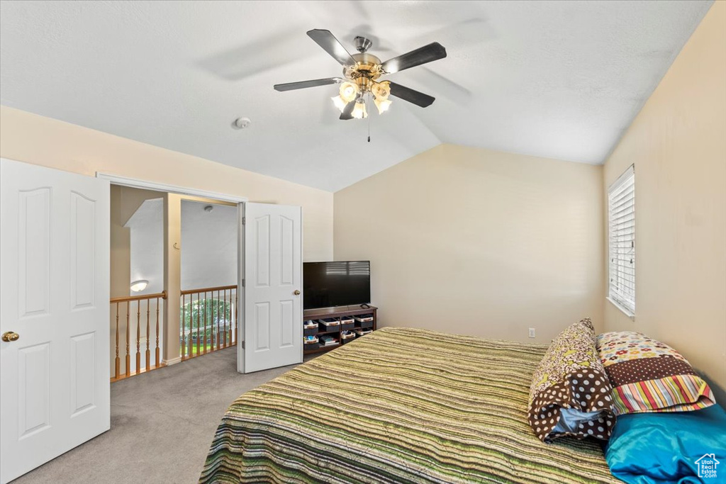 Carpeted bedroom featuring vaulted ceiling and ceiling fan