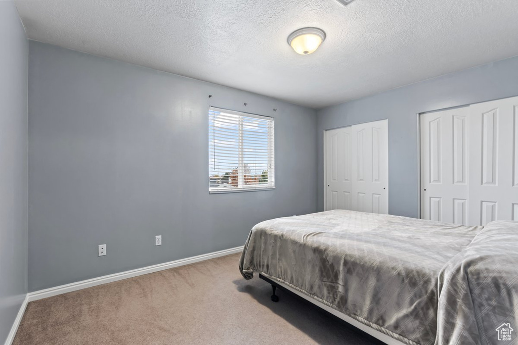 Bedroom featuring a textured ceiling, carpet flooring, and two closets