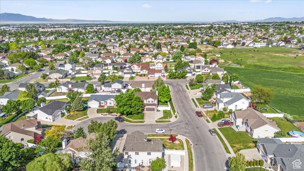Aerial view of property and surrounding area with a mountain backdrop and nearby suburban area