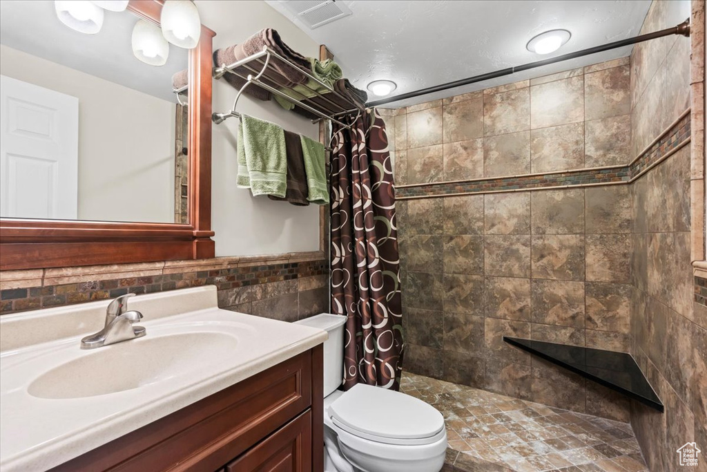 Bathroom featuring curtained shower, vanity, and toilet