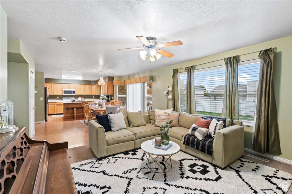 Living room featuring a textured ceiling, light wood-type flooring, and ceiling fan