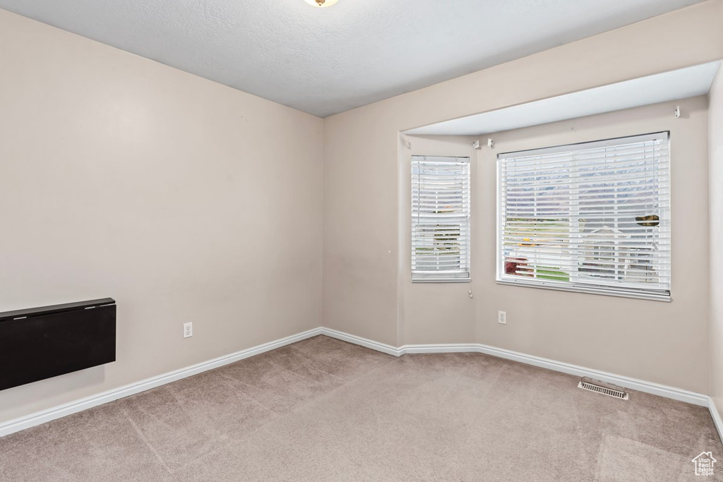 Spare room with a textured ceiling and light colored carpet