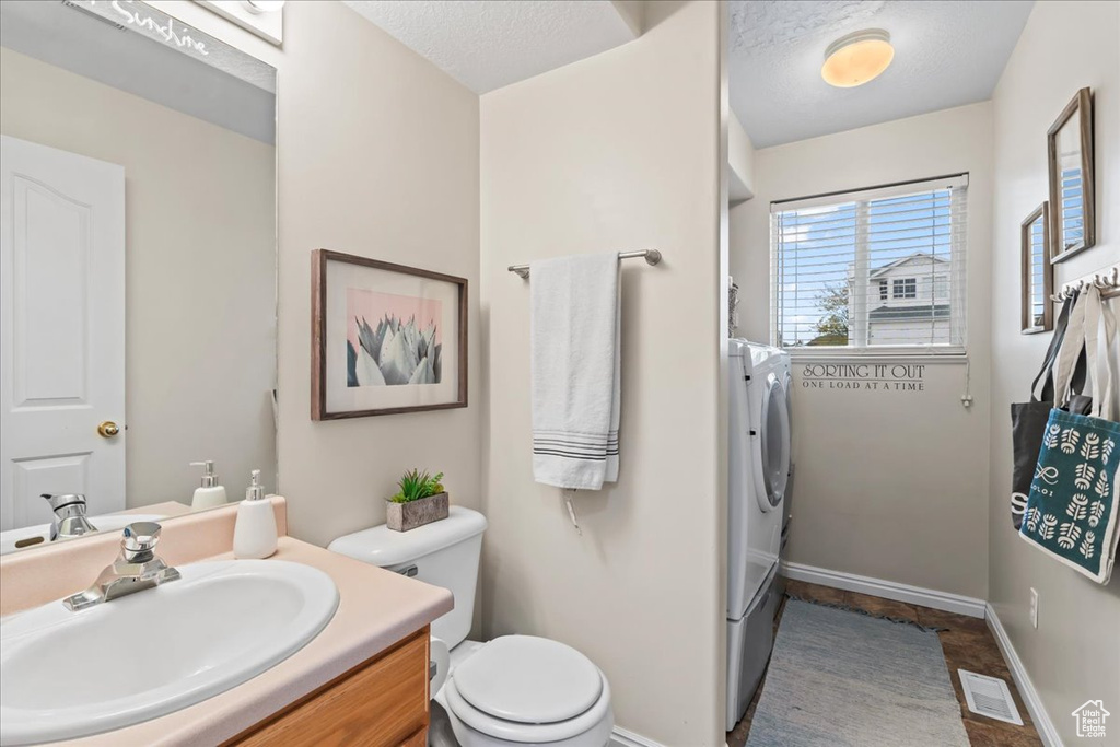 Bathroom with vanity, a textured ceiling, toilet, and independent washer and dryer