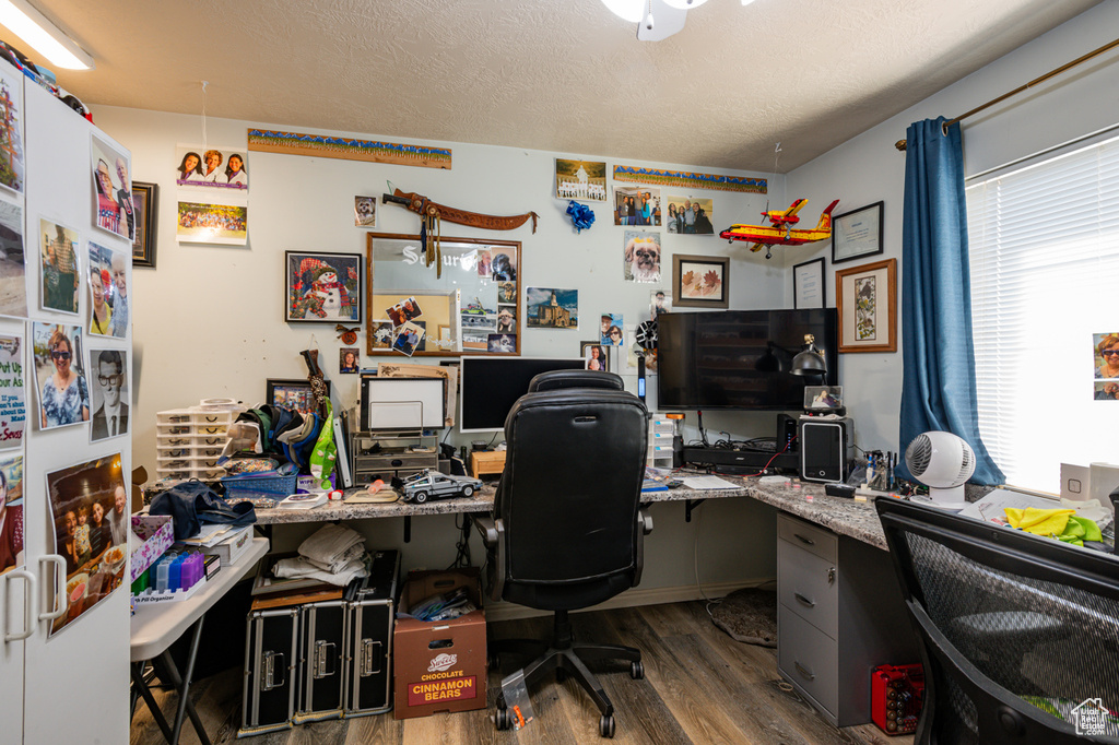 Office with dark wood-type flooring, built in desk, and a textured ceiling