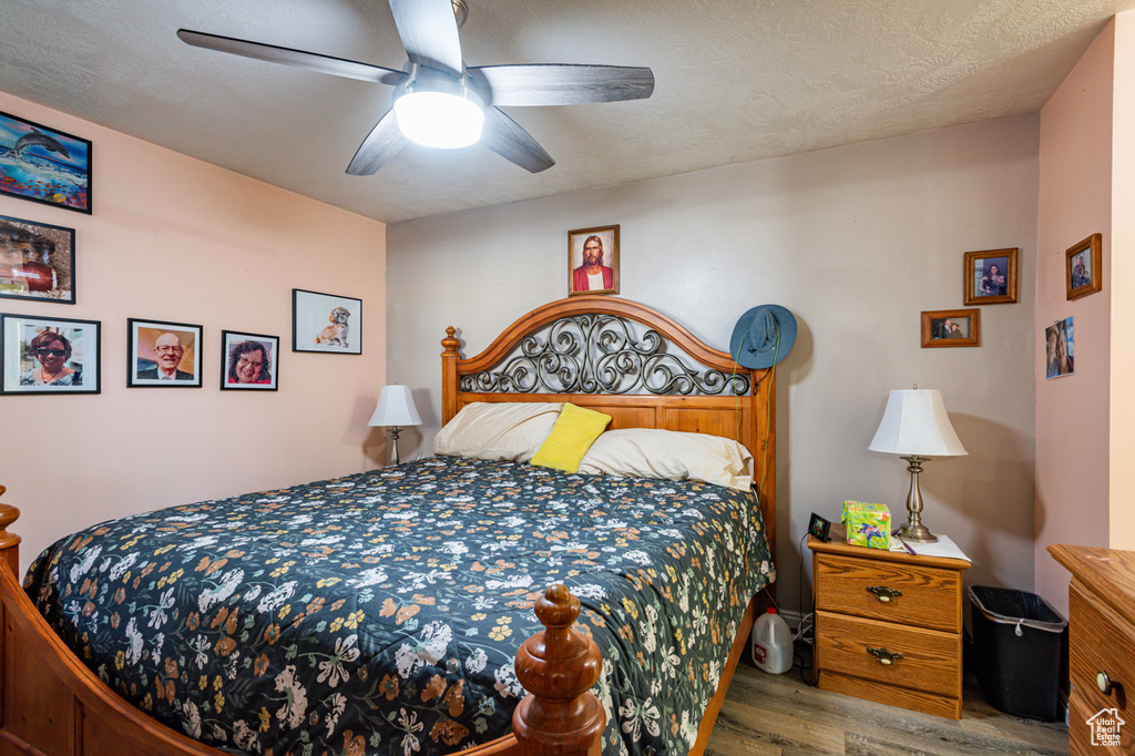 Bedroom with light hardwood / wood-style floors, a textured ceiling, and ceiling fan