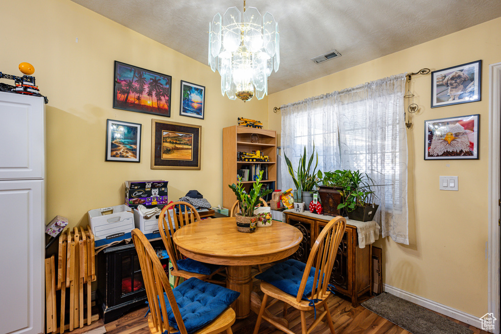 Dining area with a chandelier, wood-type flooring, and a textured ceiling