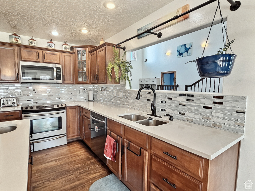 Kitchen featuring tasteful backsplash, a textured ceiling, stainless steel appliances, sink, and pendant lighting