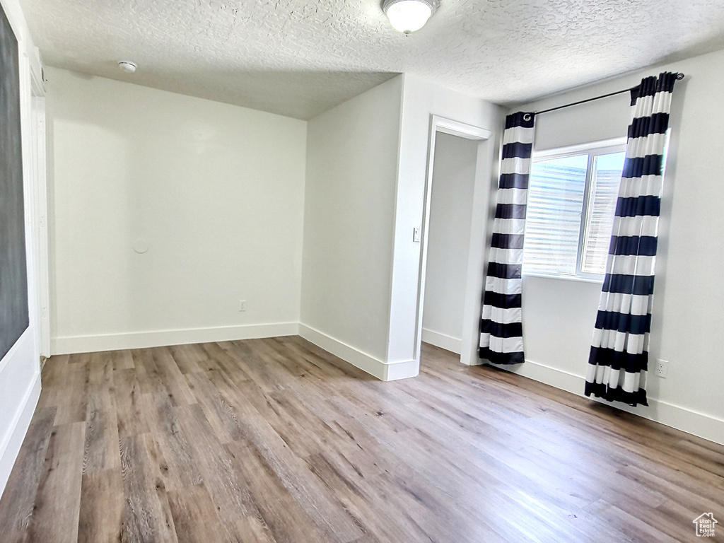 Spare room featuring a textured ceiling and light hardwood / wood-style flooring