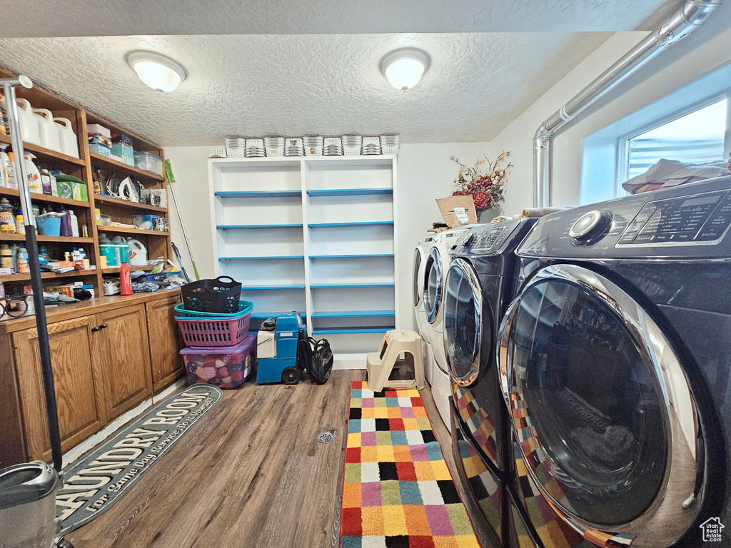 Washroom featuring wood-type flooring, a textured ceiling, and independent washer and dryer