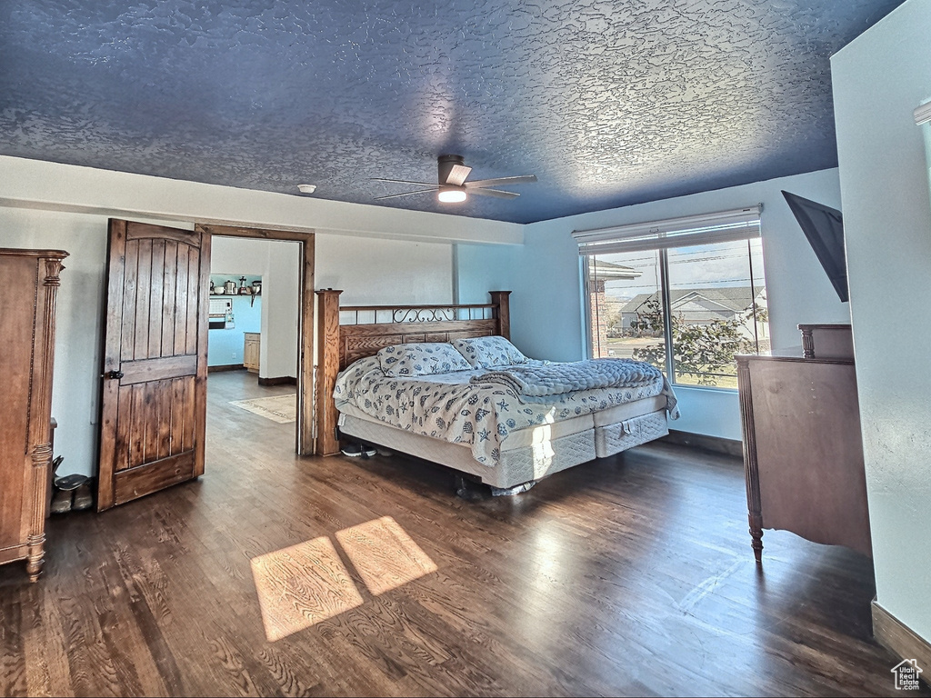 Bedroom with a textured ceiling, ceiling fan, and dark wood-type flooring